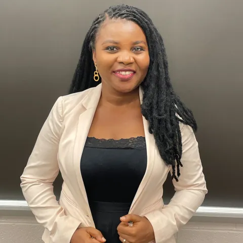 Adeyemi Odudimu wearing a black shirt and ivory jacket smiling for her headshot