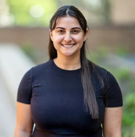Graduate student Andrea Dorsa standing in front of brick building wearing a black t-shirt.