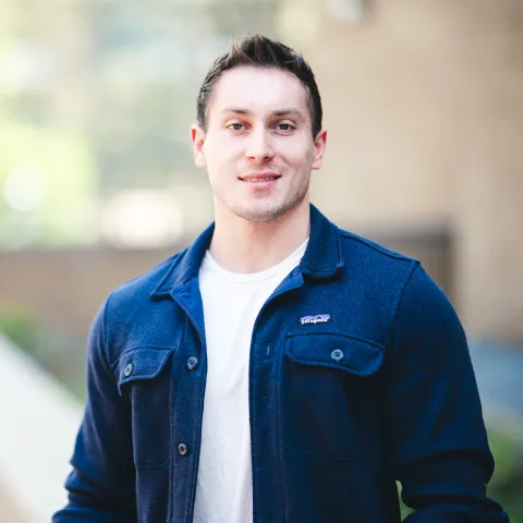Anthony Paolo standing in front of a brick building for his headshot wearing a blue shirt.