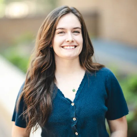 Domenica Fertal wearing a teal shirt smiling outside in front of a brick building.
