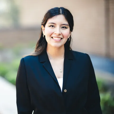 Gisselle Rojas standing in front of a brick building for her headshot wearing a black jacket.