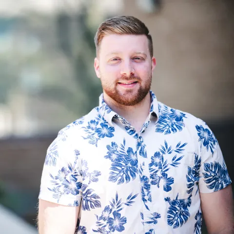 Innocenzo Martellucci standing in front of brick building for his headshot wearing a blue and white flowered shirt.