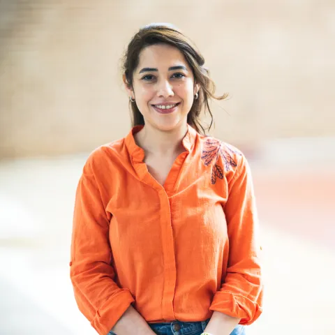 Sanaz Hashemipour wearing an orange shirt for her headshot outside.