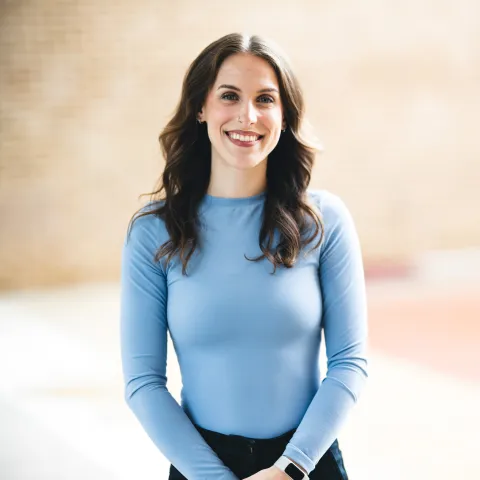 Sophia Rizzo wearing a blue long sleeve shirt smiling for her headshot outside.