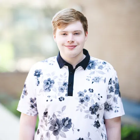 Vinnie Andrews wearing a black and white polo shirt smiling for a headshot outside.